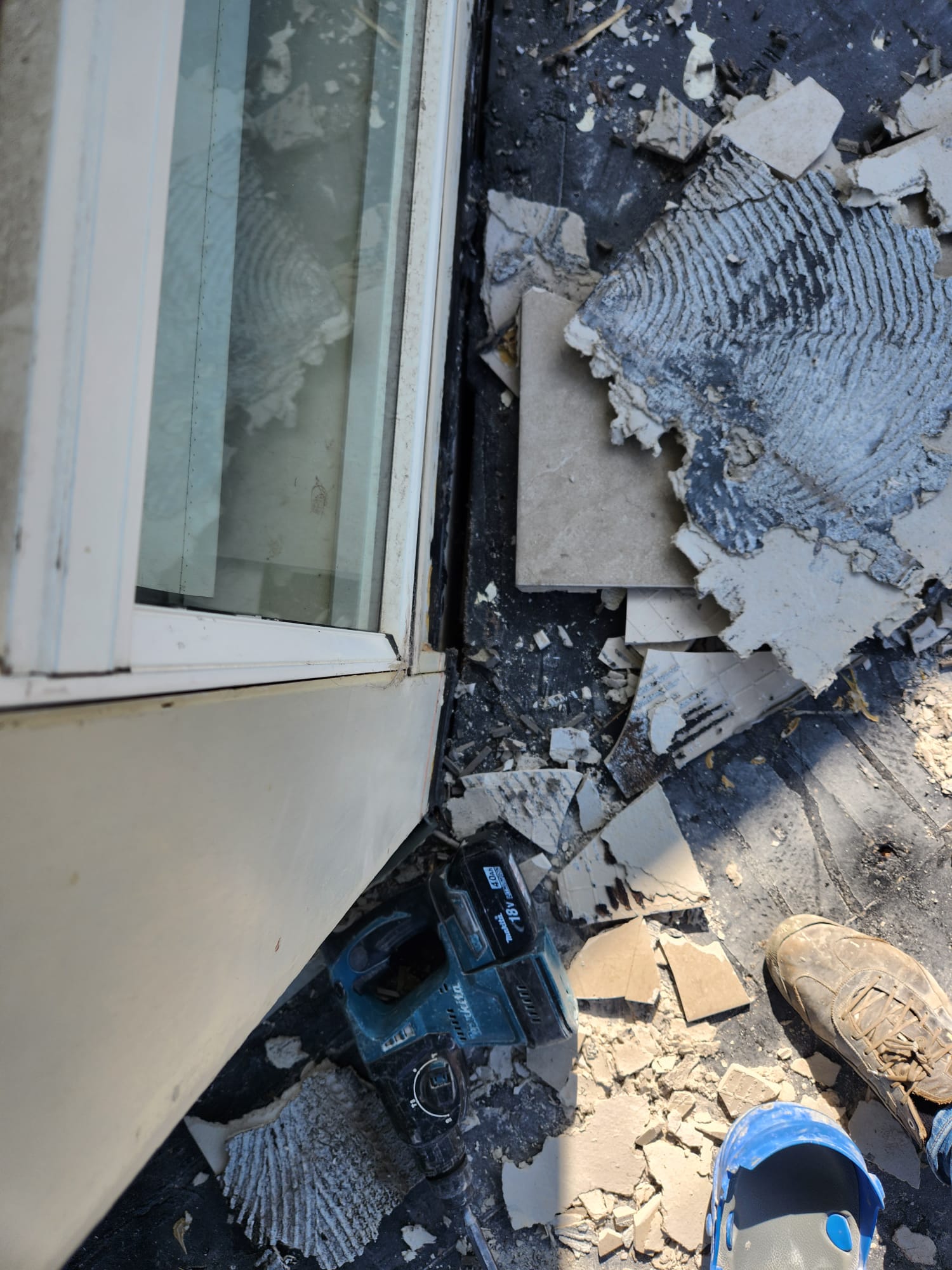 Balcony tile removal close-up near the sliding door threshold