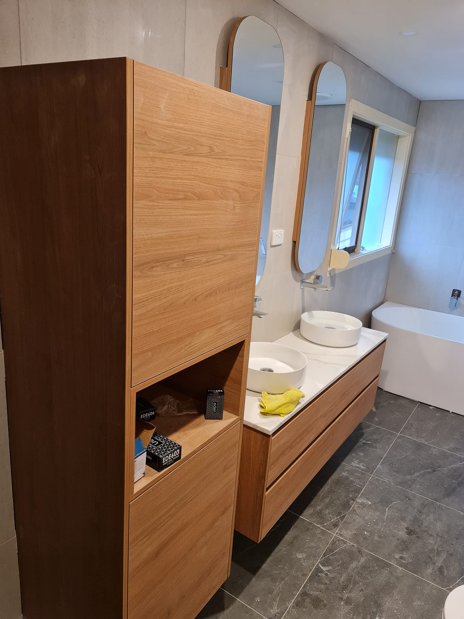 Linen tower cabinetry beside the double vanity and freestanding bath