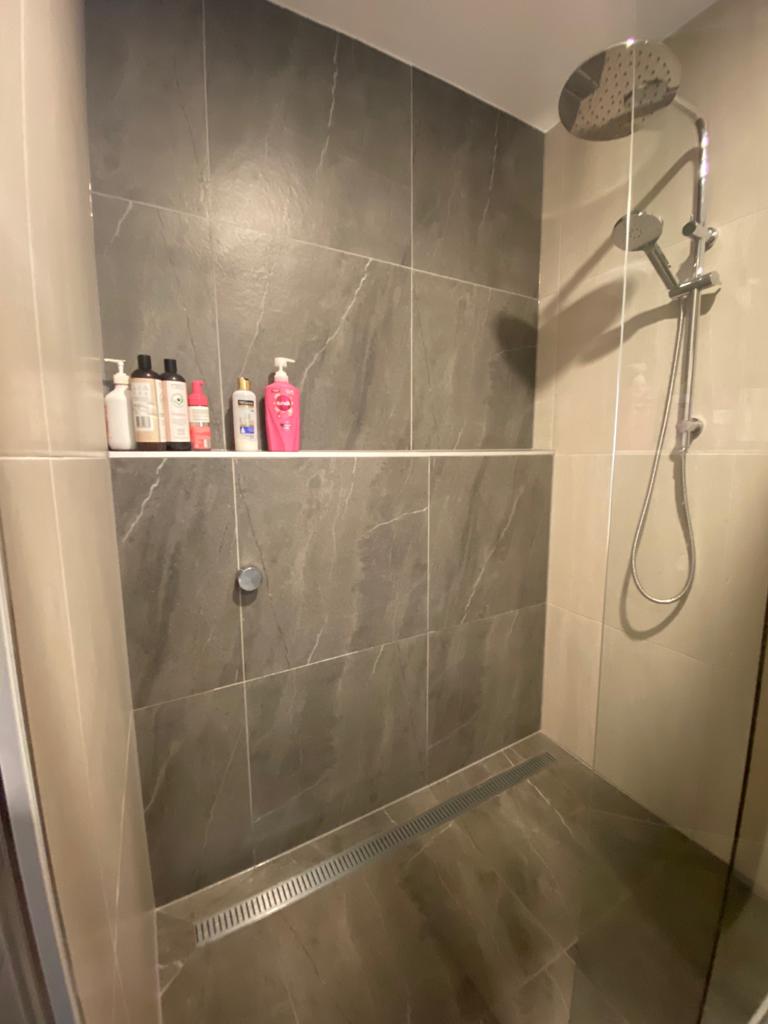 Built-in shower shelf detail with chrome fittings and linear drain