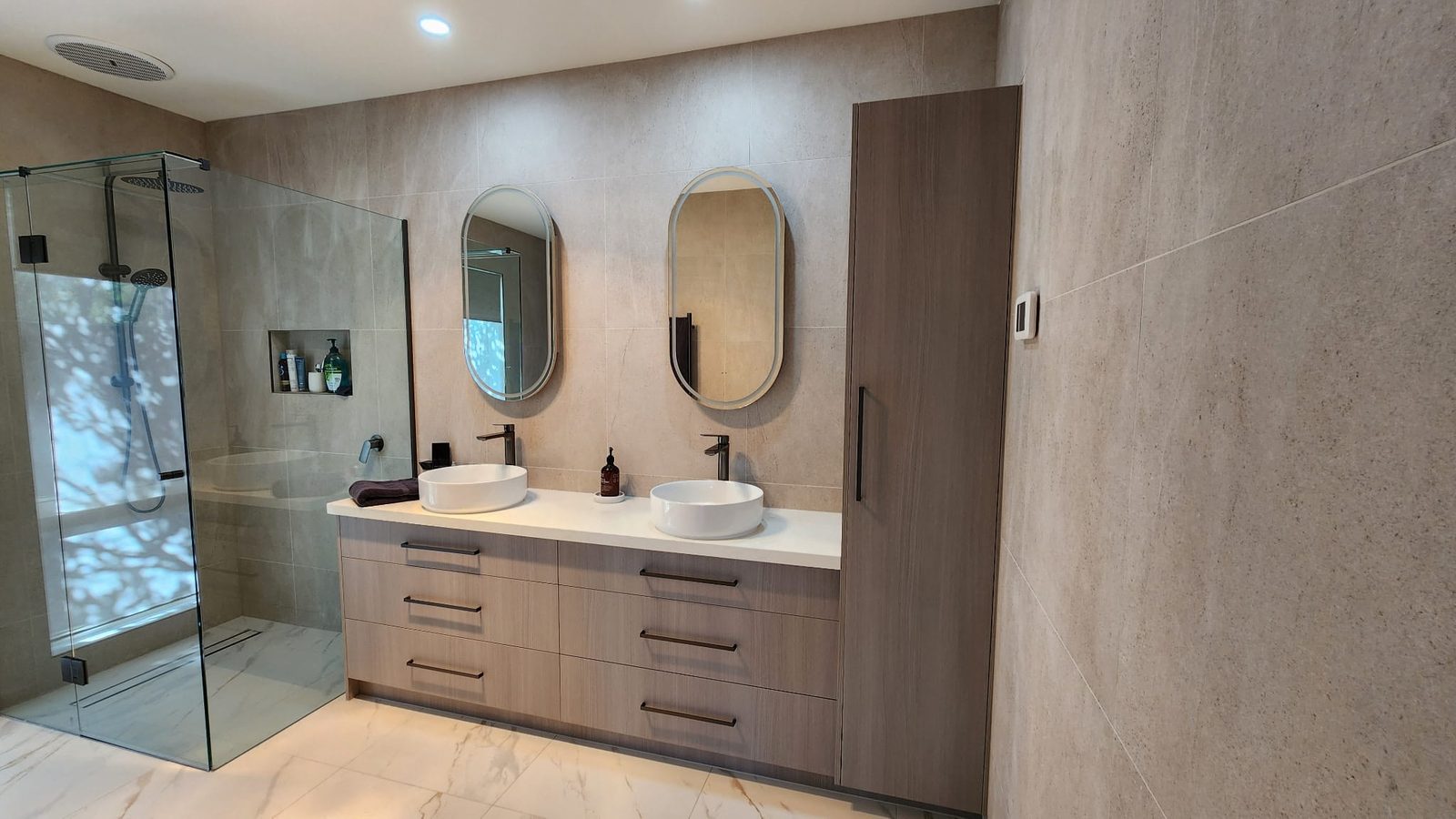Finished Armstrong Creek bathroom with limestone-look walls, double floating vanity and frameless shower