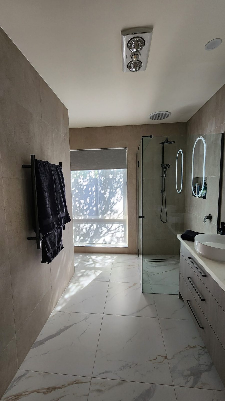 Matte black towel rail and frameless glass shower beside the window in an Armstrong Creek bathroom