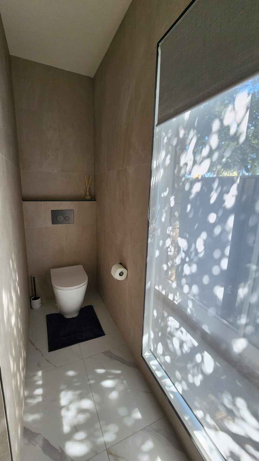 Separate toilet nook with wall-hung pan, in-wall cistern and matte black flush plate