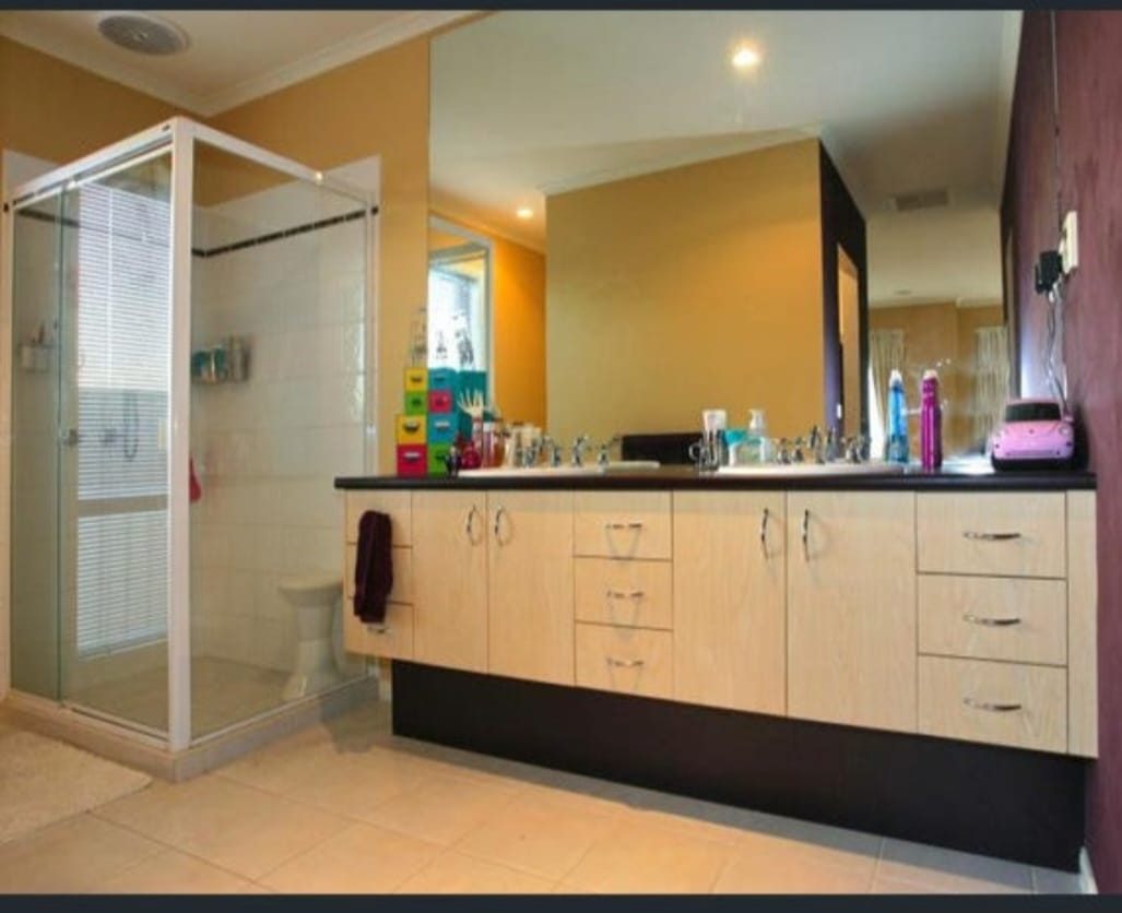 Original Armstrong Creek bathroom before renovation, with a framed shower screen, laminate vanity and cream walls