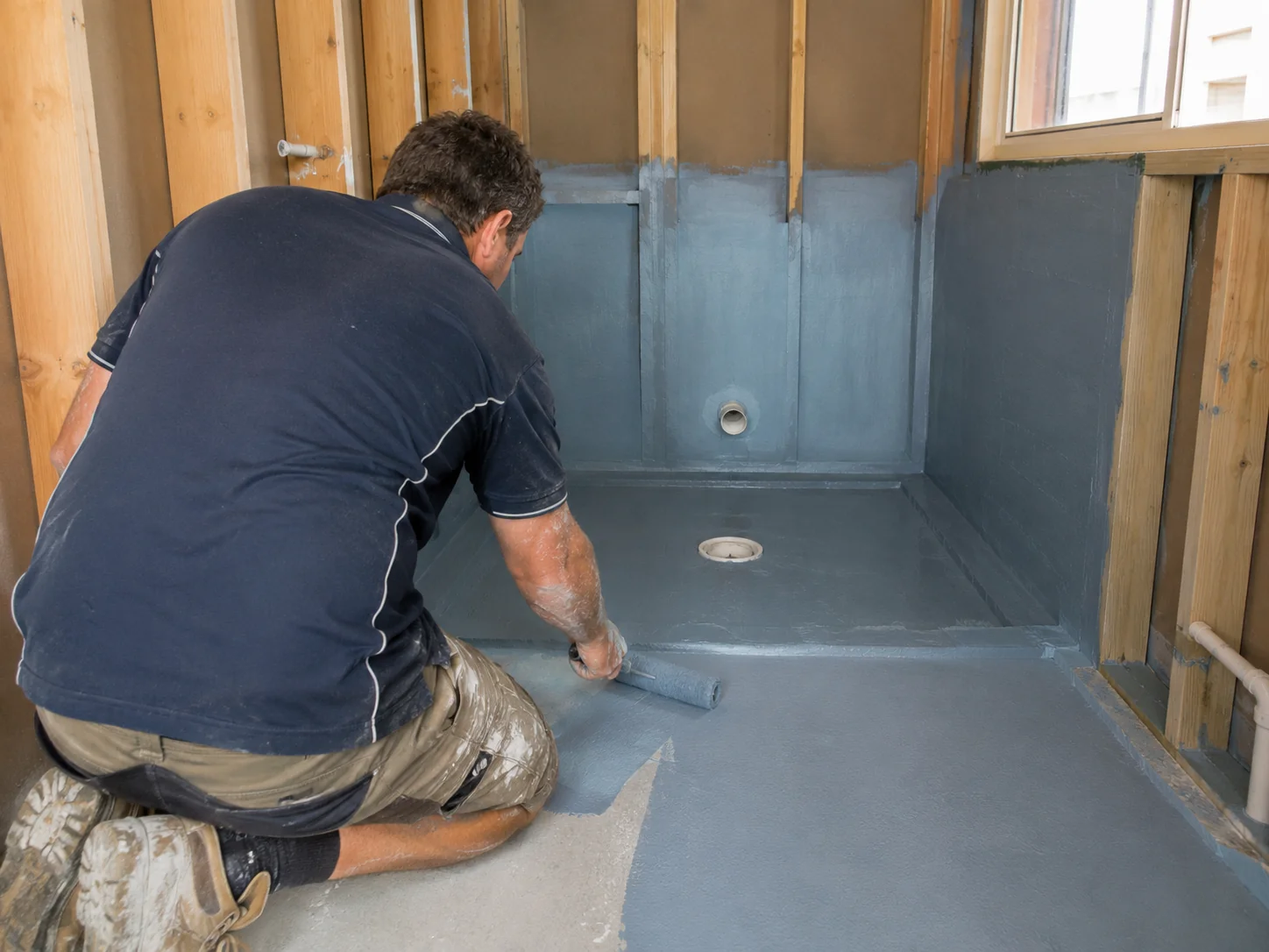 Tradesperson applying AS 3740 compliant waterproofing membrane in a Geelong bathroom before tiling