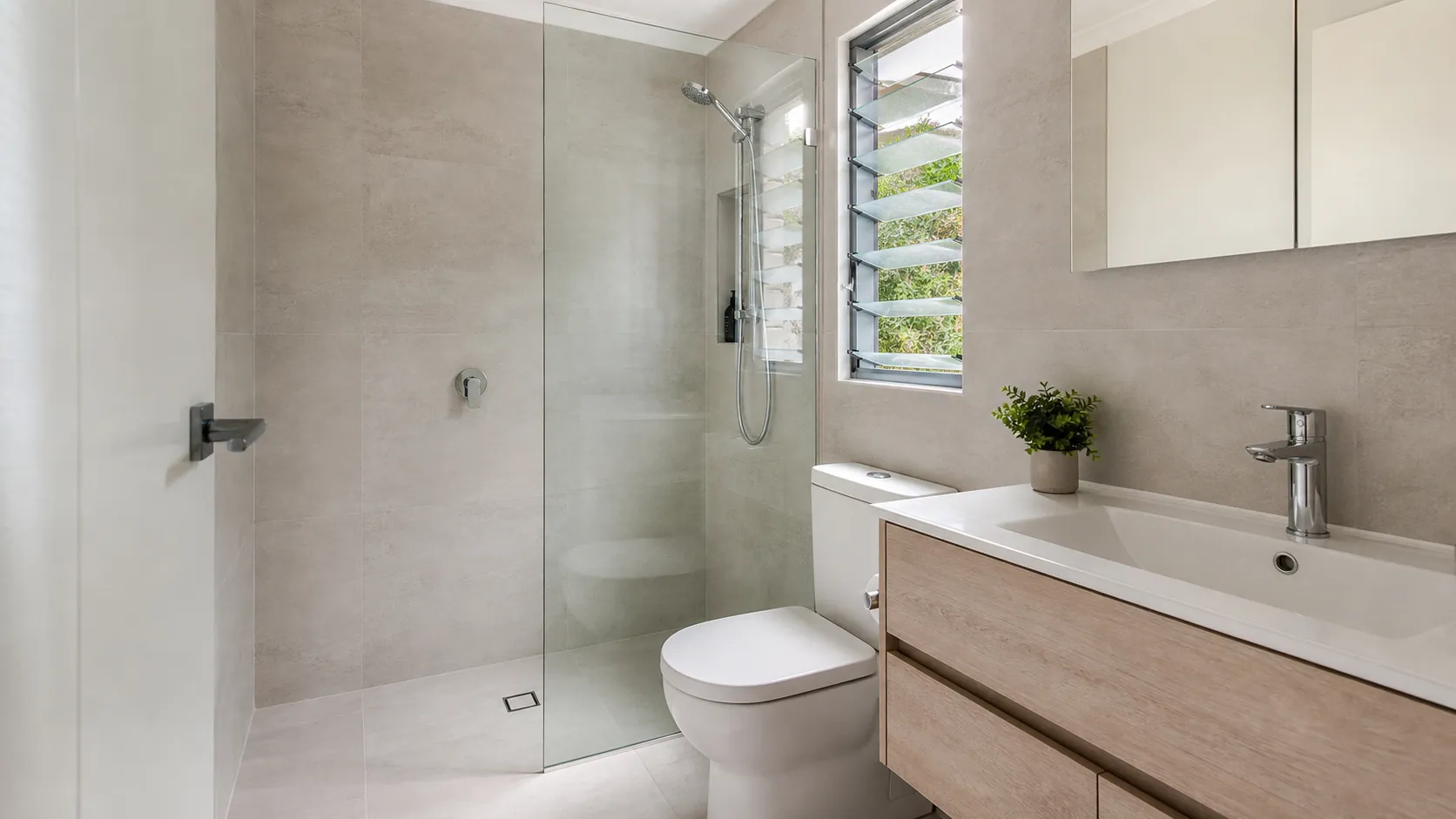 A laundry converted into a bathroom with a shower, toilet and vanity, and the laundry moved to a cupboard