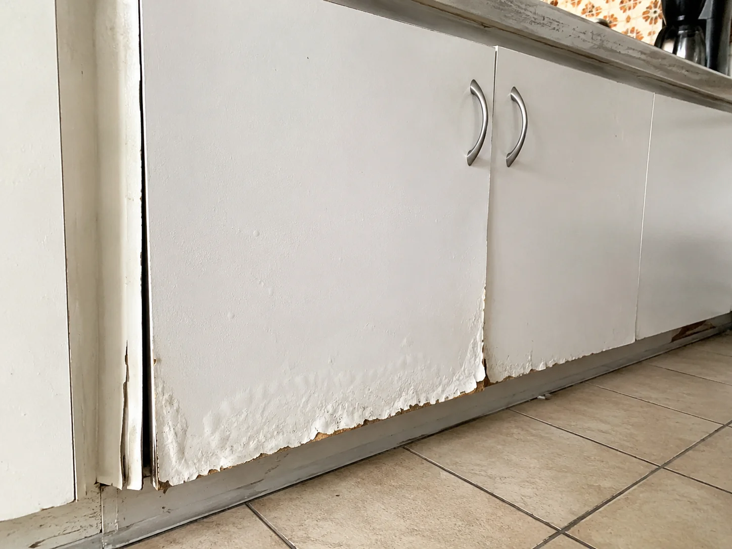 Kitchen cabinets with water damage and swollen doors — a facelift won't fix structural cabinet issues