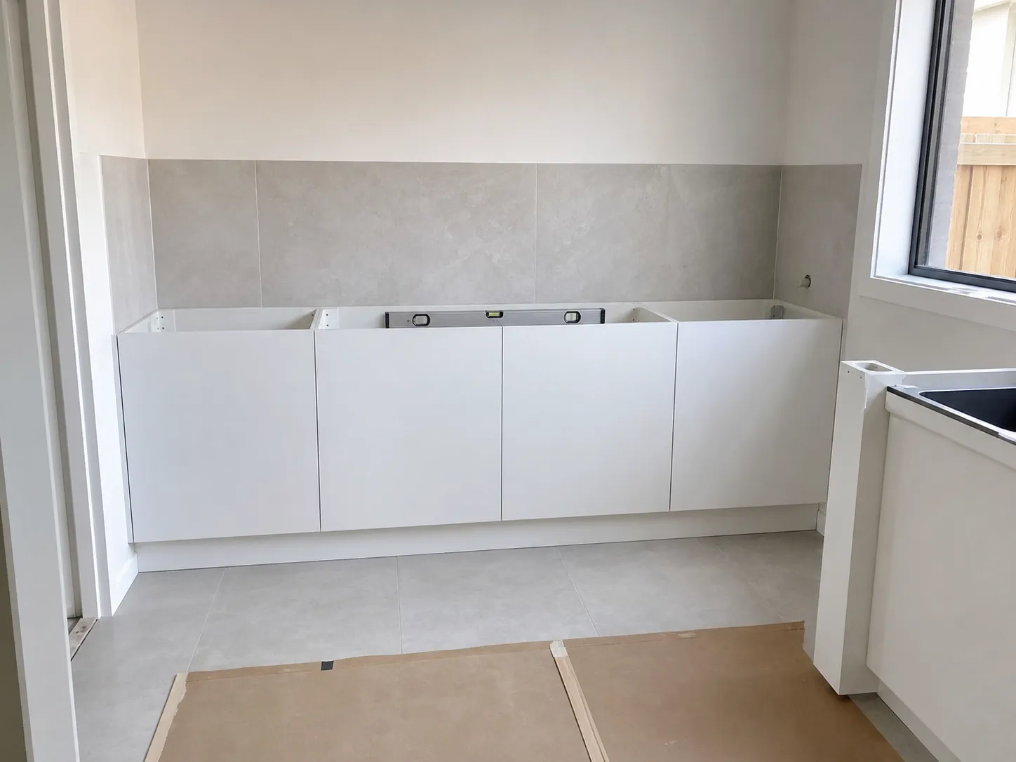Laundry with base cabinets installed and tiled floor in place, waiting for the benchtop and trough