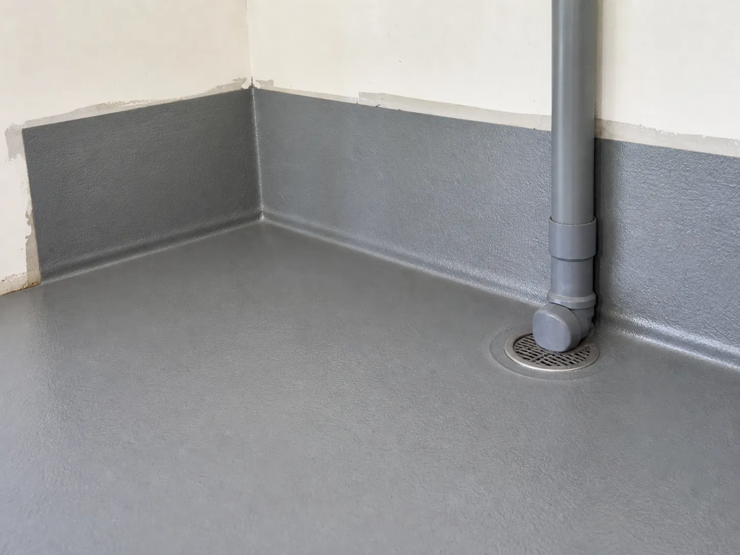 Laundry floor and lower wall with a water-resistant coating applied at the floor and wall junction before tiling