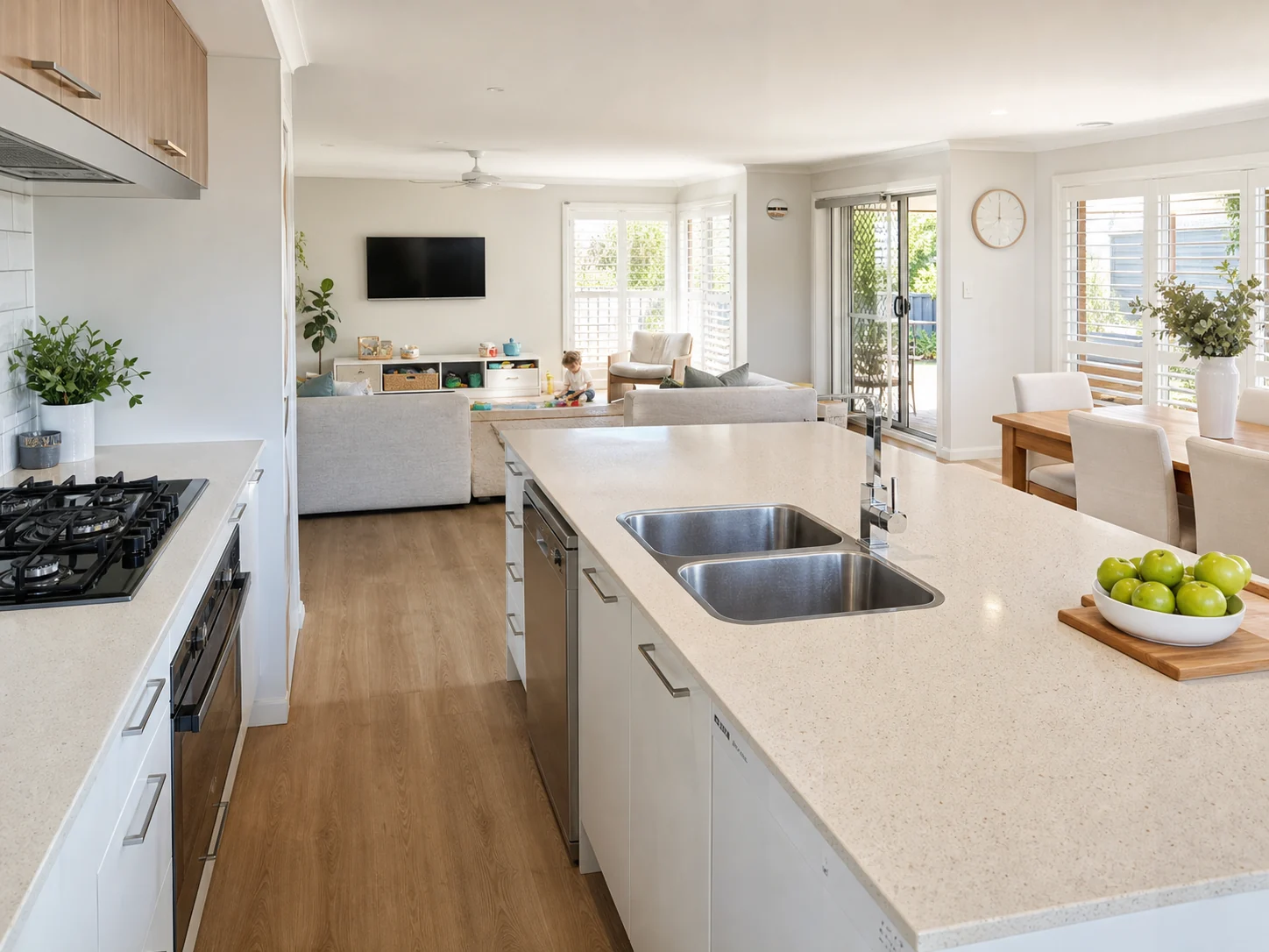 Open-plan kitchen connected to a living area, allowing a parent to cook while supervising children in the adjoining space