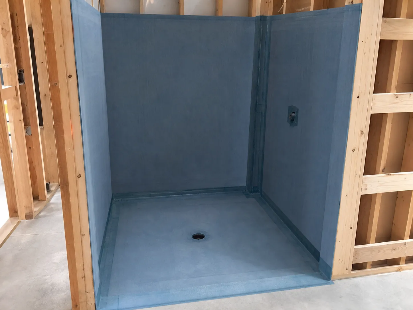 A shower recess mid-renovation showing waterproofing membrane extending up the walls to bathroom standard
