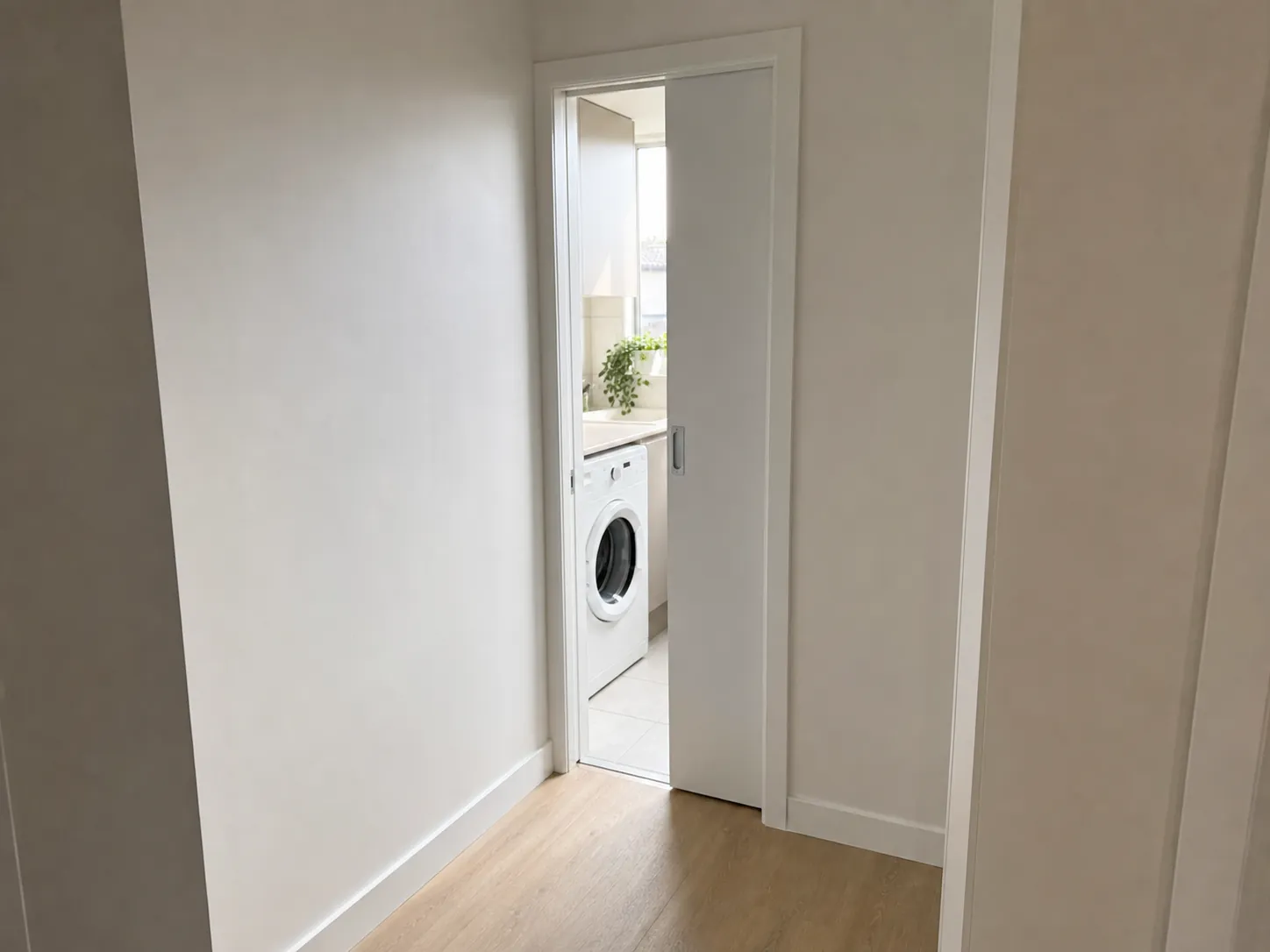 Narrow laundry entry fitted with a sliding cavity door instead of a swinging door to save floor space