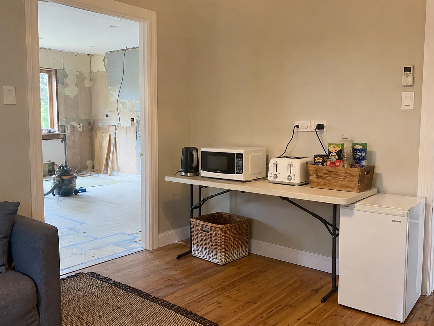 Temporary kitchen setup in a living area during a Geelong home renovation — kettle, microwave and bar fridge on a folding table
