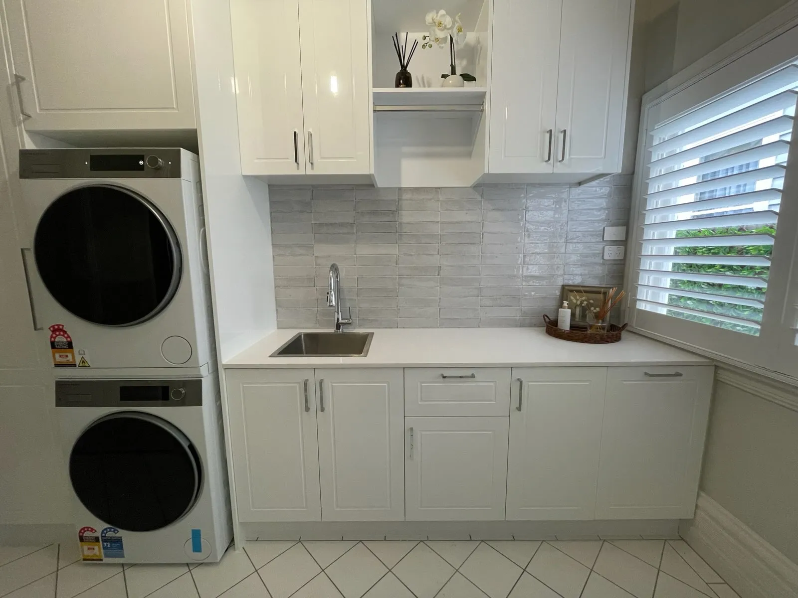 Geelong West laundry renovation with stacked appliances, white shaker cabinetry and grey splashback tiles