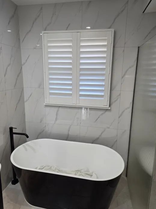Black freestanding bath against Calacatta marble tile