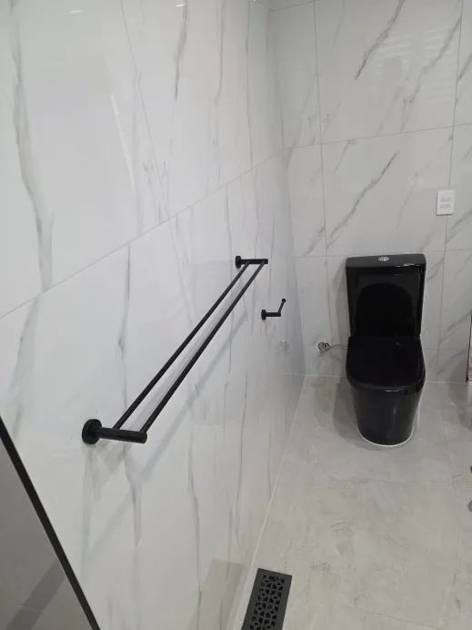 All-black toilet and matte black double towel rail against marble tile