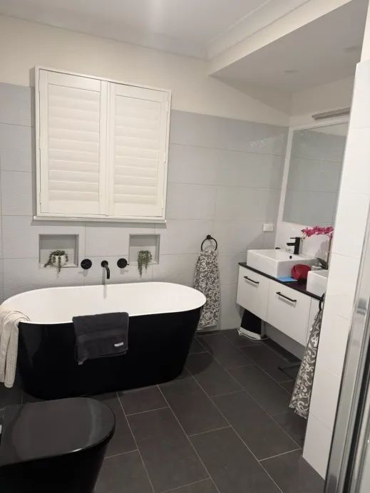 Before — existing bathroom with white vanity and dark floor tiles