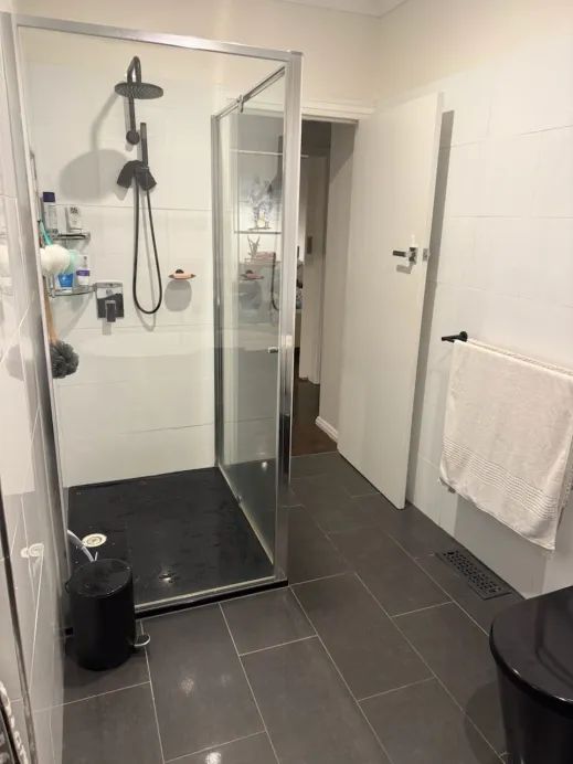 Existing shower zone with partial wall tiles and a framed screen