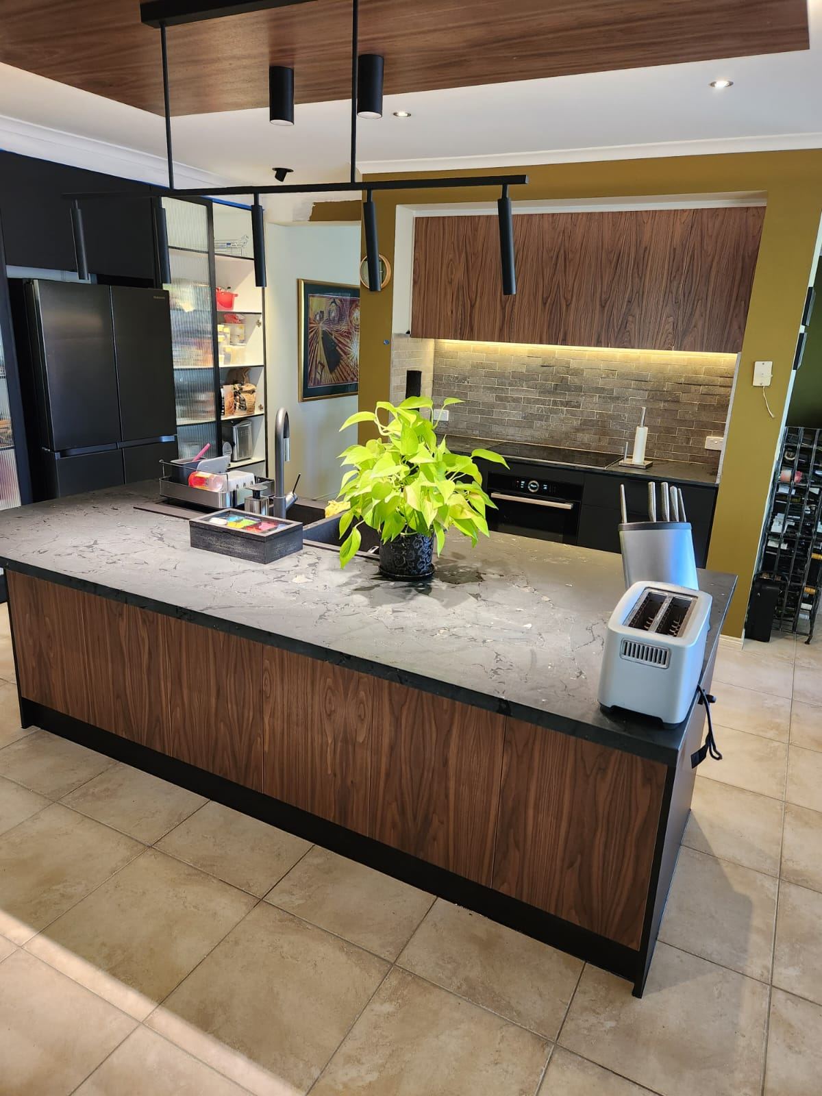 Finished Point Cook kitchen with walnut cabinetry and waterfall stone island