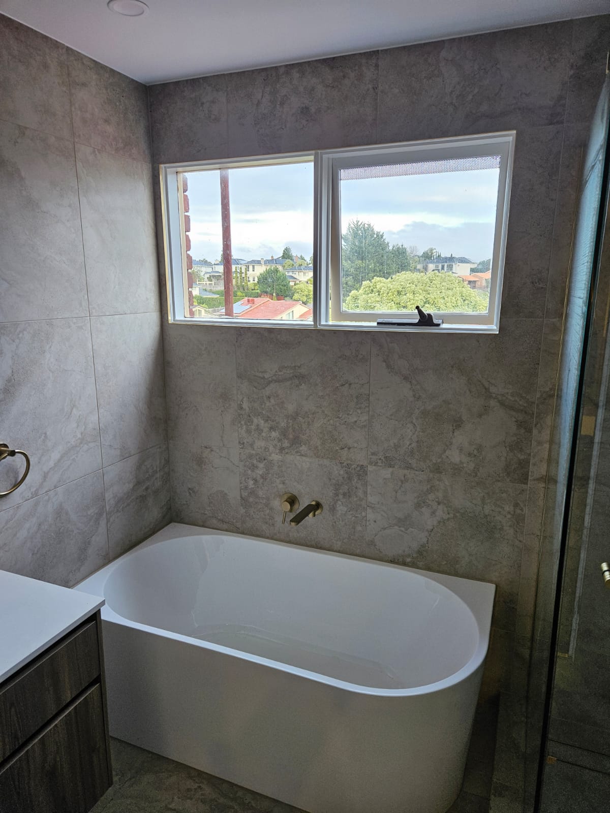 Freestanding bath under the window with a wall-mounted brass tap
